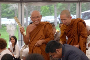 Luang Por Liem sprinkles blessings on the assembled guests, while Tan Suvijjano holds the water bowl