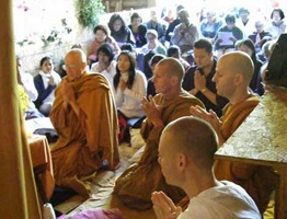 The Sangha chants a blessing in front of the standing Buddha statue