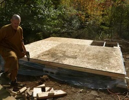 Ajahn Kusalo works on the floor of the new utility building