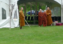 Monastics wait by the tent as guests as the guests start to arrive for Vesak