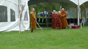 Monastics wait by the tent as guests as the guests start to arrive for Vesak